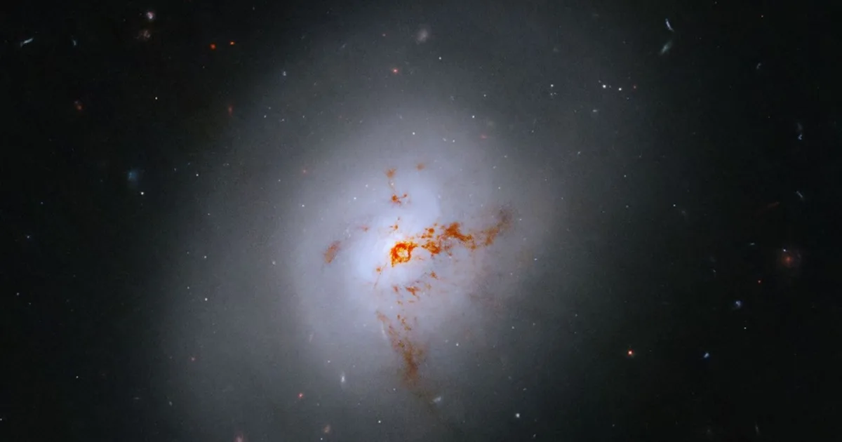 A bright core, rusty brown dust lanes, and faint ghosts of spiral arms. The little coloured dots in the background are not stars. They are entire other galaxies, much further away. Image: NASA, ESA, K. Alatalo (STScI); Image Processing: G. Kober (NASA/Catholic University of America).