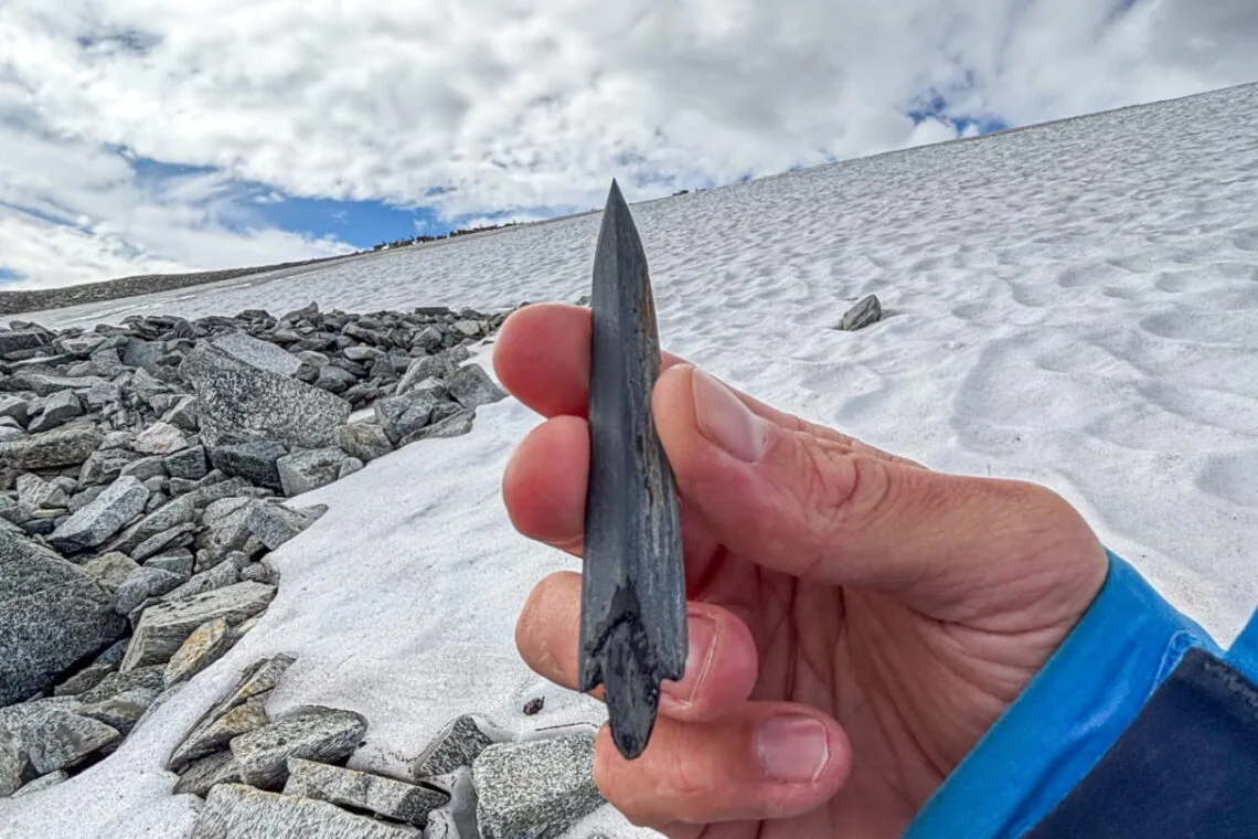 A slate arrowhead with its wooden shaft, roughly 5,000 to 6,000 years old, recovered from melting ice in the Kvitingskjølen mountain area of Jotunheimen. Photo credit belongs to Secrets of the Ice / Innlandet County Municipality; illustrative image shown here.